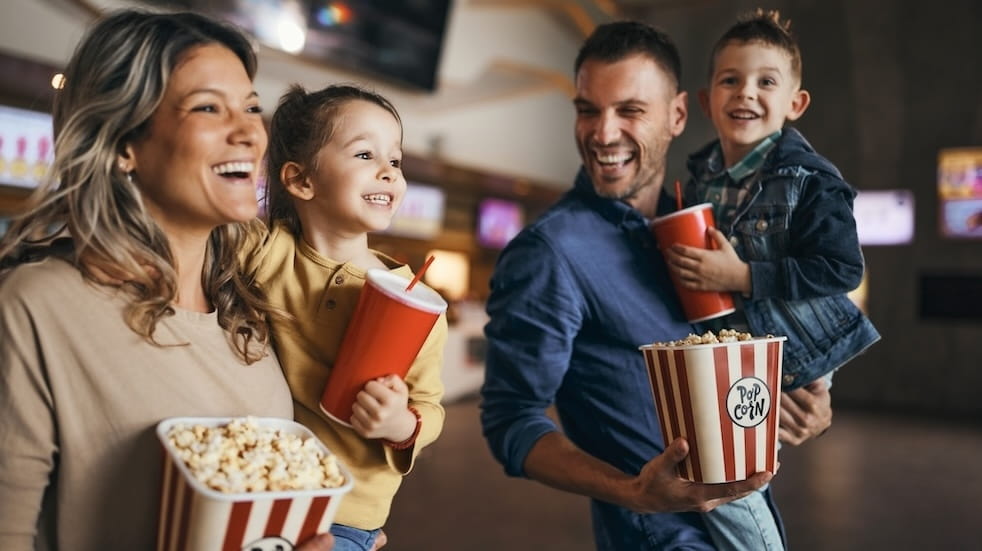 Happy family enjoying while walking with popcorn and drinks in cinema